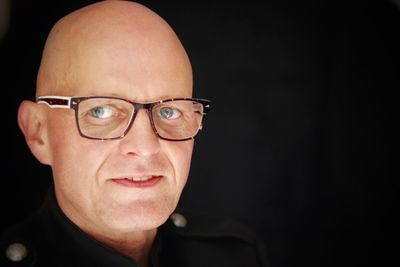 Portrait of man wearing eyeglasses against black background