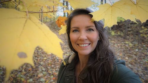 Portrait of smiling young woman standing during autumn