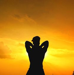 Silhouette man standing against orange sky