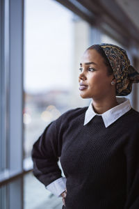 Young woman looking through window