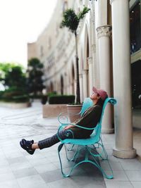 Woman looking up while relaxing on bench in city