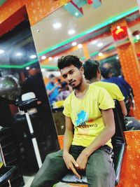 Full length of smiling man sitting in store