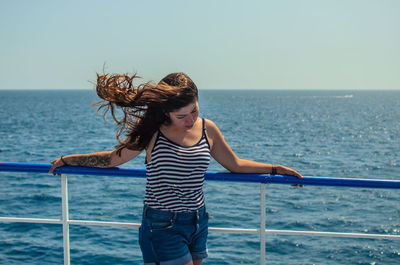 Young woman standing by sea against sky