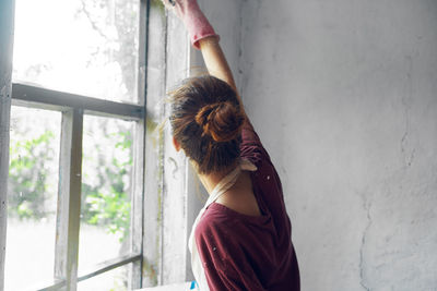 Beautiful woman standing by window at home