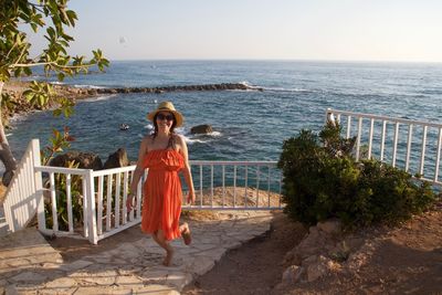 Smiling woman standing against sea at beach