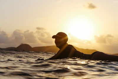 Female surfer lying on surfboard in the evening