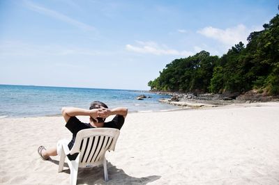 Man sitting on beach and looking at sea