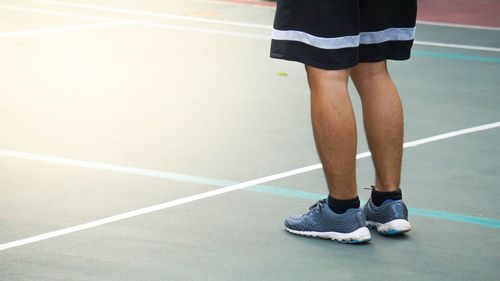 Low section of man standing on tennis court