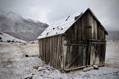 House on field by snowcapped mountain against sky