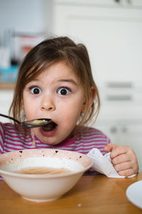 Portrait of cute girl eating food at home