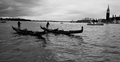 Men sailing boat in sea against sky