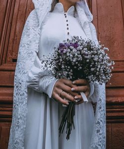 Midsection of bride holding flower
