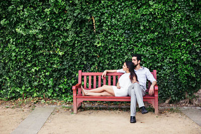 Couple relaxing while sitting on bench at park