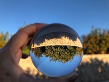 Close-up of hand holding glass against clear blue sky