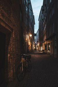 Bicycle parked on street amidst buildings in city at night