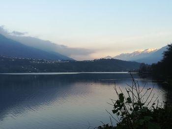 Scenic view of lake by mountains against sky during sunset