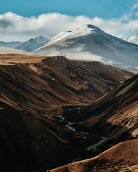 Scenic view of snowcapped mountains against cloudy sky