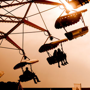 Low angle view of silhouette swing ride against sky