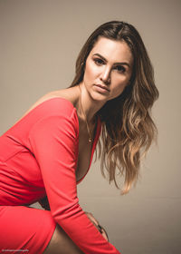 Portrait of beautiful young woman against wall