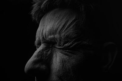 Close-up of man with eyes closed against black background