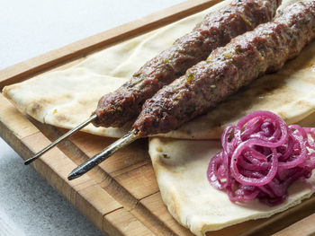 Close-up of fresh shish kebab lamb meat on skewers over wooden cutting board