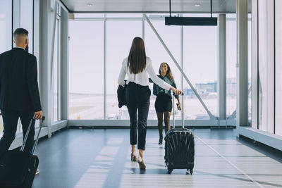 Smiling businesswoman walking towards female colleague in corridor at airport