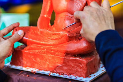 Cropped image of sculptor painting statue