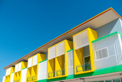 Low angle view of yellow building against clear blue sky