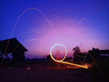 Light trails on field against sky at night