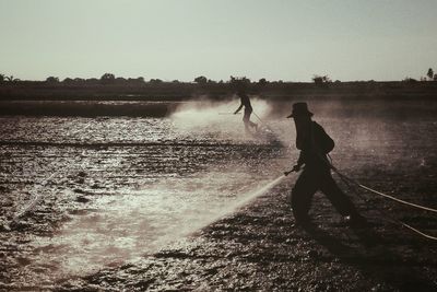 Rear view of man walking on beach against clear sky