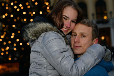 A young couple in love hugs at the christmas market.
