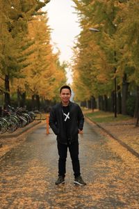 Full length portrait of young man standing on street during autumn