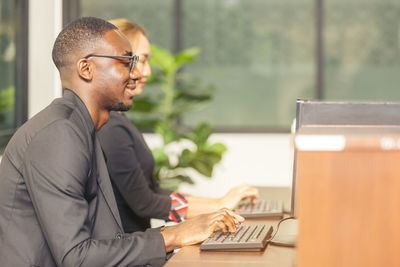 A black man works on a tablet computer in the hotel lobby.