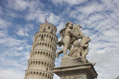 Statues and leaning tower of pisa against cloudy sky