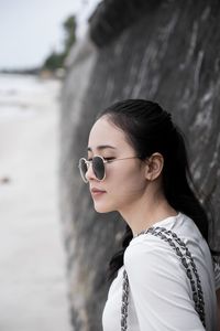 Young woman wearing sunglasses by rock formation