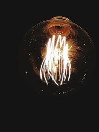 Close-up of illuminated light bulb against black background