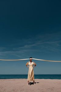 Rear view of man standing on beach against sky