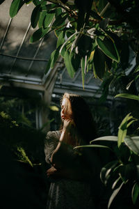 Portrait of a young woman amidst plants during sunset