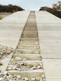 Surface level of footpath by stone wall against sky