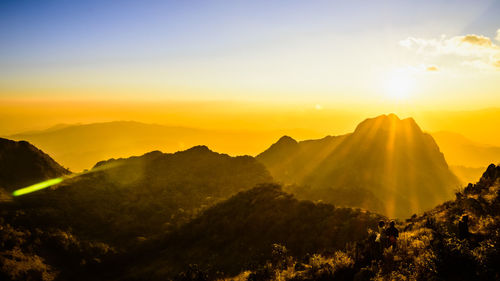Beautiful mountain peaks topped with vivid sky, cloud and blast horizon sun and camera flares