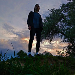 Low angle view of man standing against sky during sunset