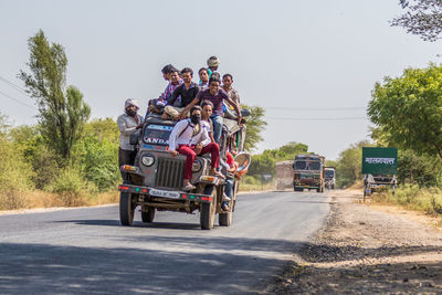 People riding motorcycle on road against sky