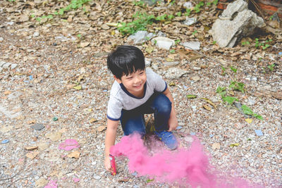 Full length of boy with distress flare crouching on ground