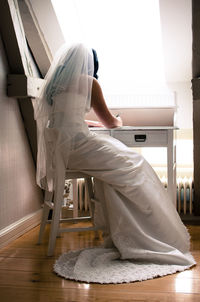 Side view of woman sitting on chair at home