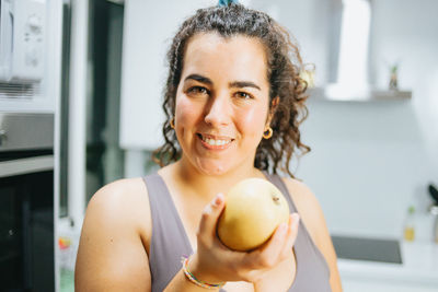 Portrait of young woman eating fruit at home