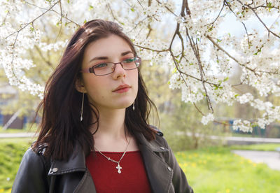 Portrait of beautiful young woman standing by flowering plant