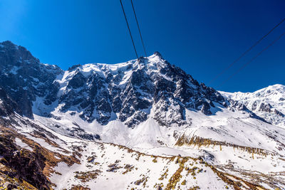 Scenic view of snowcapped mountains against clear blue sky