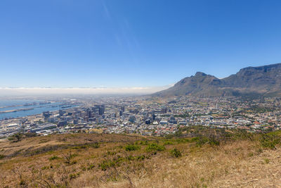 Aerial view of townscape and mountains against blue sky