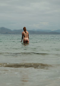 Rear view of woman swimming in sea against sky