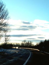 Road by trees against sky